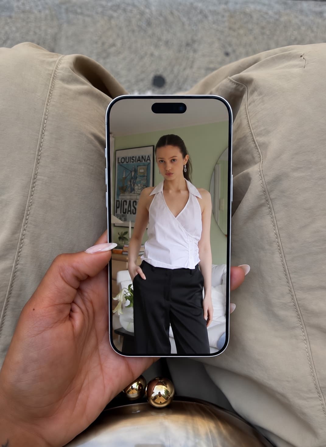 A phone held in one hand, showing a redesign preview of the same shirt.